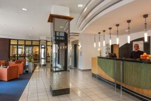 a lobby of a hotel with a man standing at a counter at IntercityHotel Freiburg in Freiburg im Breisgau