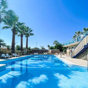 a large swimming pool with palm trees in the background at Villaggio Camping Duca Amedeo in Martinsicuro