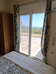 a bedroom with a bed and a large window at Villa Klelia in Afantou