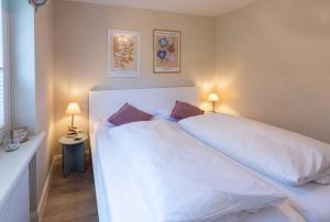a bedroom with a large white bed with two pillows at Strandlust im Haus Caecilia in Wenningstedt