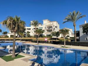 a swimming pool with palm trees in front of a building at Casa Serena - Sucina in Sucina