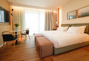 a hotel room with a large bed and a table at Laguna Faro Suites - Adults Only in Grado +56 photos