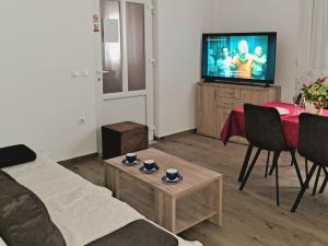a living room with a couch and a table and a television at Holiday apartman in Kaštela