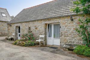 a stone house with a white door and a chair at L'auberge du Fumoir d'Armen in Plogoff