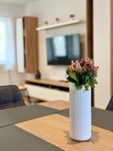 a white vase with flowers sitting on a table at hygge-flats Apartment für 2-6, WLAN, Homeoffice in Heppenheim an der Bergstrasse