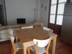 a dining room with a wooden table and white chairs at Apartamento La Carmela in Utrera