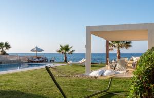a hammock on the lawn next to the ocean at Hersonissos Beach Villa in Hersonissos