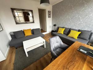 a living room with a gray couch and yellow pillows at Komfortable und gepflegte Ferienwohnung für zwei bis vier Personen mit separatem Bad und separater Küche in Bad Segeberg