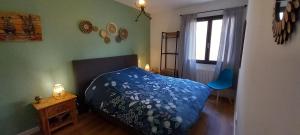ein Schlafzimmer mit einem Bett mit einer blauen Bettdecke in der Unterkunft Appartement avec terrasse dans maison individuelle in Ceyreste