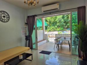 a living room with a table and a balcony at Samed Your House Family Room in Ko Samed