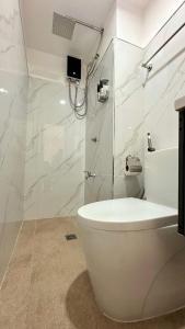 um banheiro branco com vaso sanitário e chuveiro em Burnham Hill 2BR Condo em Baguio