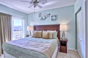 a bedroom with a bed with a ceiling fan and a window at Sunset Vistas 206S in St Pete Beach +52 photos