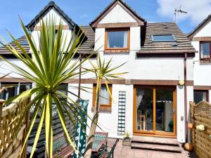 ein Haus mit einer Palme davor in der Unterkunft Waterside Holiday Cottage on Camel Trail Wadebridge Sleeps 5 in Wadebridge