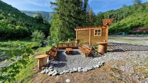 a small wooden cabin with a bench and logs at Chata vo Vyhnanej - Terchová in Terchová