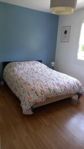 a bed in a bedroom with a colorful bedspread at Chez MONIQUE in Sainte-Marguerite