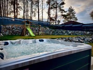 a jacuzzi tub in a yard with a playground at Chata ARMA in Vrbov