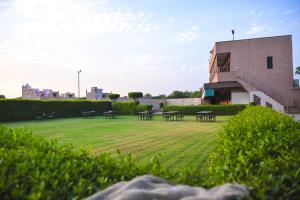 un prato con tavoli e sedie di fronte a un edificio di Apple Resort & Restaurant a Jodhpur