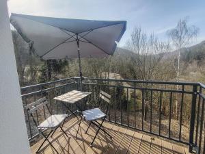 a table and two chairs on a balcony with an umbrella at Haus Charlottenburg 1, zentrumsnah gelegen, mit Blick auf die Festung in Königstein an der Elbe