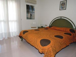 a bed with an orange and black comforter in a bedroom at Spacious apartment with terrace and pool in Bibione in Bibione +31 photos