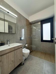 a bathroom with a toilet and a sink and a shower at Luxe benedenwoning Nula Kos in Kos +34 photos