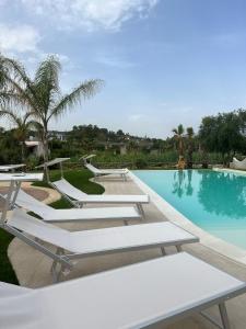 a swimming pool with white lounge chairs next to it at Le Onde della Sicciara in Balestrate