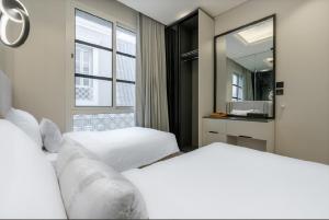 two white beds in a room with a mirror at شقة بتصميم انيق مقابل الافنيوز d11 in Riyadh