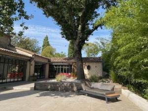 a couch sitting under a tree in front of a house at Maison de campagne Proche de St Emilion in Montcaret