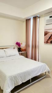 a bedroom with a white bed and a window at Casa de Porch in Manila