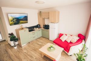 a living room with a red couch and a kitchen at Oliv Apartament in Zalău