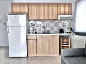 a kitchen with a white refrigerator and wooden cabinets at SUNNY 2, Two-bedroom house with parking in Komotini