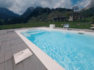 a large swimming pool with a chair and mountains at Hotel Vienna in San Martino di Castrozza