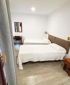 two beds in a hotel room with white sheets at Habitaciones triple familiar HOTEL LAUAXETA in Mungia