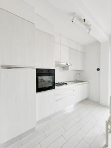 a white kitchen with white cabinets and a stove at Thomas House on Train Tracks in Venice