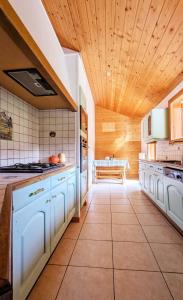 una cucina con mobili bianchi e soffitto in legno di Chalet Sterenn, 10 personnes, Grand Bornand et La Clusaz a Entremont
