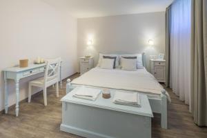 a white bedroom with a white bed and a desk at Kapri Vendégház in Badacsonytomaj