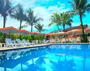 a pool at the resort with chairs and umbrellas at Hotel Camburi Praia in Camburi