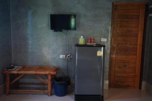 a refrigerator in a room with a table and a television at Bunma Homestay in Ban Khlong Sok