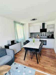 3Rooms Central Modern near MTU- Lakescape FeWos في فريدريشسهافن: مطبخ وغرفة معيشة مع طاولة وأريكة