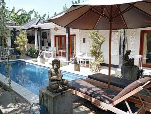 a swimming pool with a statue next to a house at Lovina House in Lovina