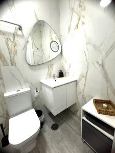 a white bathroom with a toilet and a mirror at Starfish Home in Costa Del Silencio +6 photos