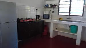 a small kitchen with a stove and a sink at Les Datchi Cottages in Diani Beach