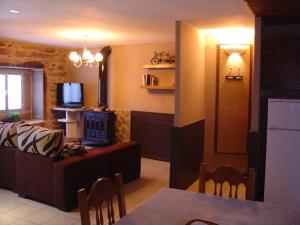 ein Wohnzimmer mit einem Sofa und einem TV sowie eine Küche in der Unterkunft Casas Lucas - Carleo in Outes