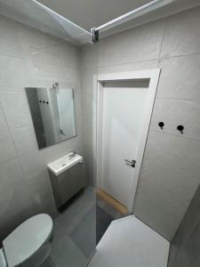 a bathroom with a toilet and a mirror and a door at The Crow Ajuda Apartment I in Lisbon