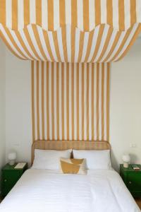 1 cama con cabecero a rayas y 2 mesitas de noche en Inn Oltremare - appartamento di design a un passo dal centro e dal mare, en Livorno