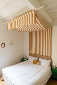1 dormitorio con cama blanca y techo a rayas en Inn Oltremare - appartamento di design a un passo dal centro e dal mare, en Livorno