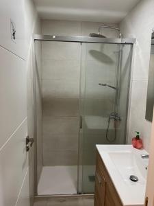 a shower with a glass door next to a sink at Albergue Azabache in Santiago de Compostela