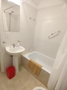 a bathroom with a sink and a tub and a toilet at La hora azul departamentos in Playas Doradas