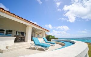 a patio with two lounge chairs and the ocean at Maltese Falcon Villa 3bd by ZenBreak in Saint Philip