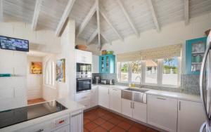 a large kitchen with white cabinets and a sink at Maltese Falcon Villa 3bd by ZenBreak in Saint Philip