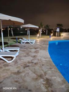 2 sillas y sombrillas junto a una piscina por la noche en appartement- Marrakech-Sapphire, en Marrakech